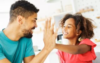 Parent giving child a high five after earning a sticker on a behavior chart, demonstrating positive reinforcement in ABA therapy in Maryland