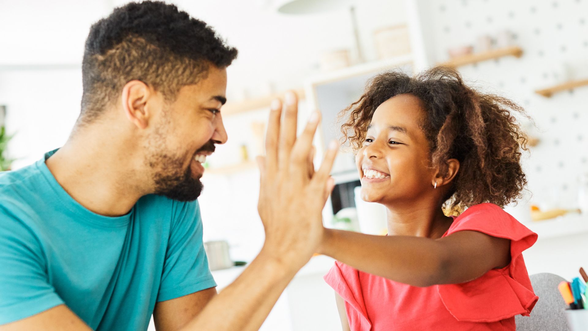 Parent giving child a high five after earning a sticker on a behavior chart, demonstrating positive reinforcement in ABA therapy in Maryland