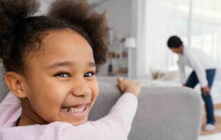 Smiling child at home during early childhood intervention near me session with supportive caregiver nearby