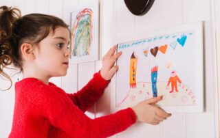 Child adjusting artwork at home as part of early release day transitions autism routine in Maryland