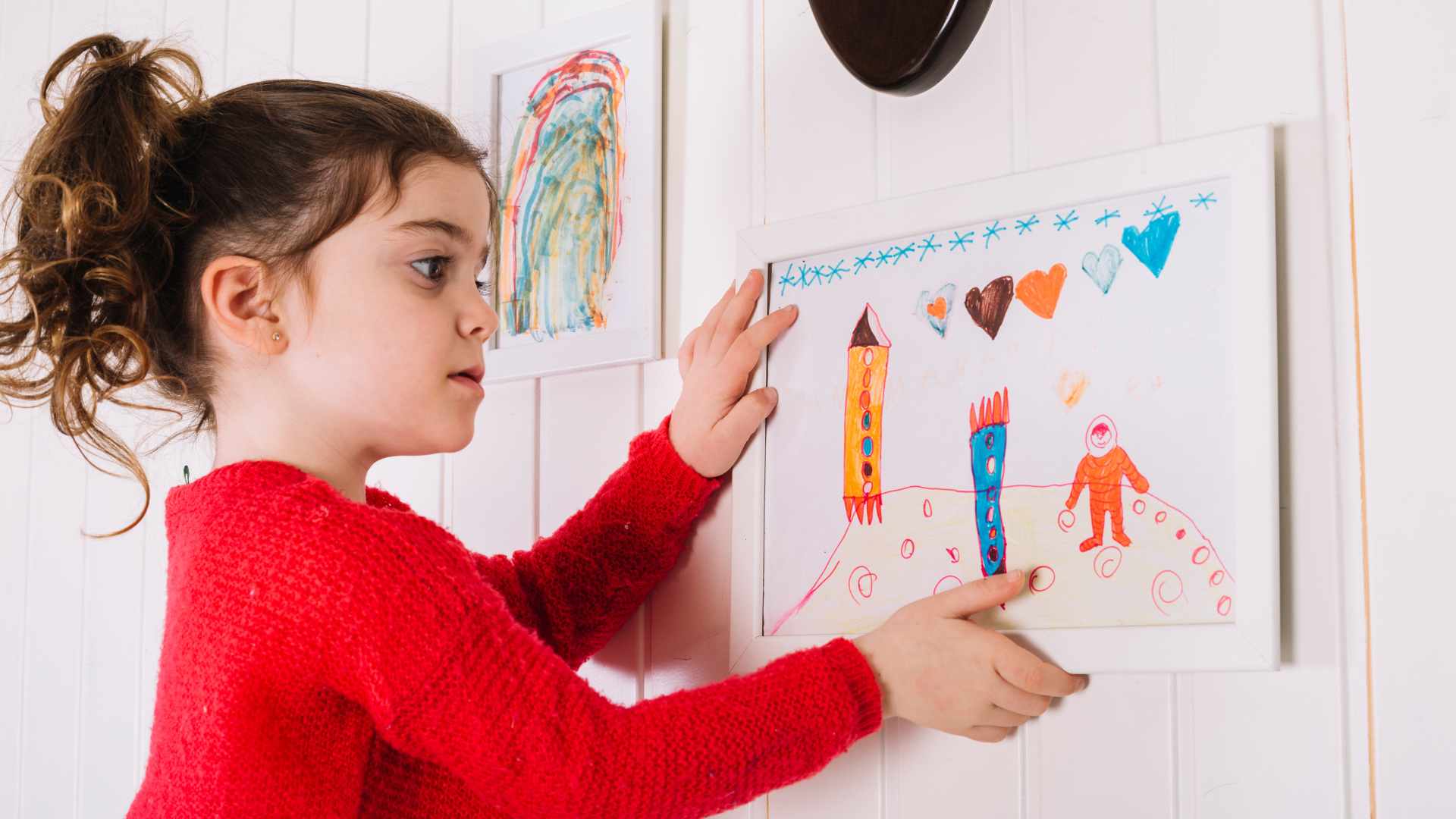 Child adjusting artwork at home as part of early release day transitions autism routine in Maryland