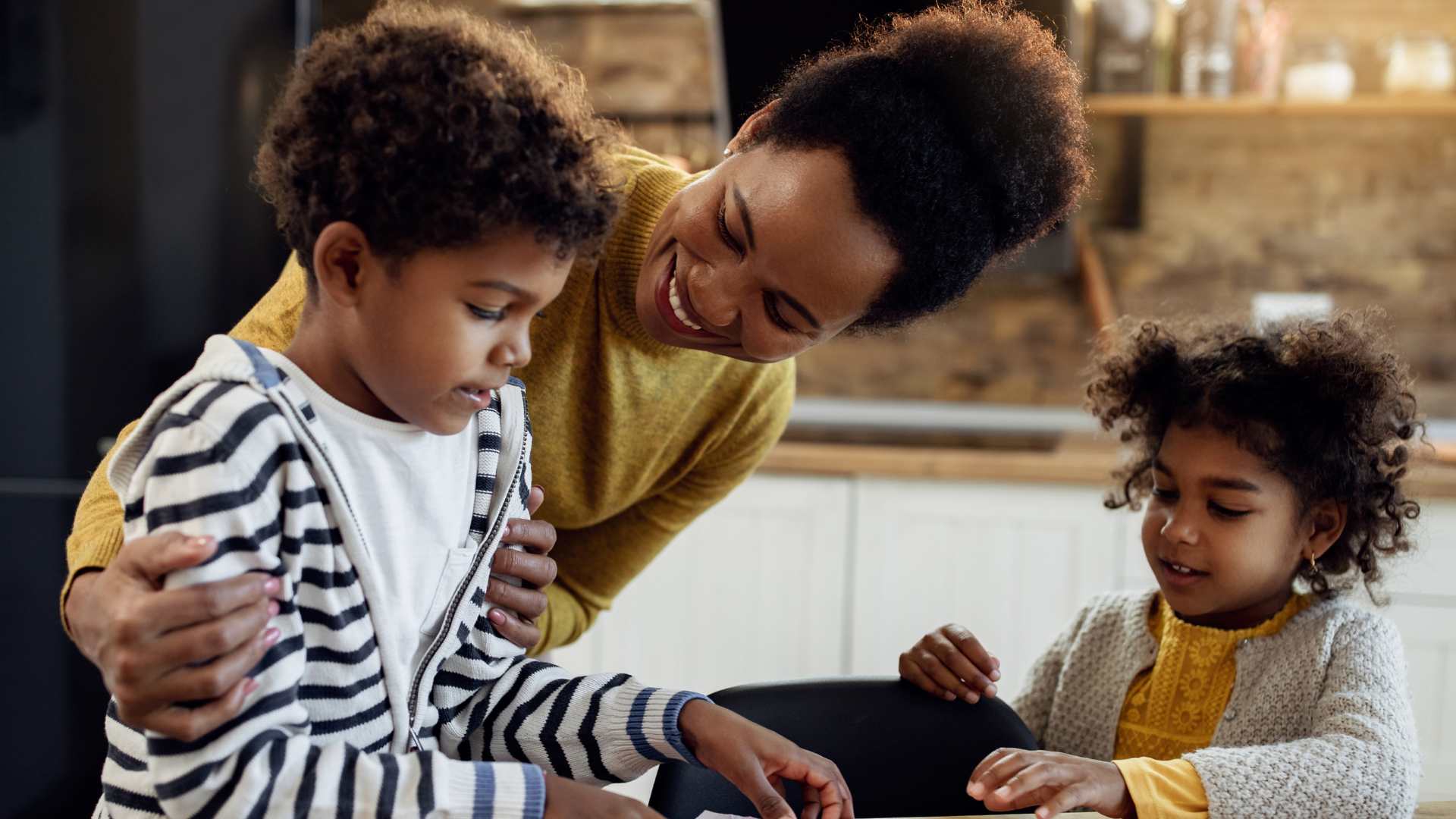 Smiling mother helping two young children with autism practice learning activities at home, supporting home school consistency through engaged parent involvement