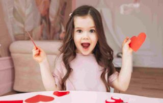 oung girl with autism joyfully making Valentine's Day paper hearts at home, preparing for classroom card exchange