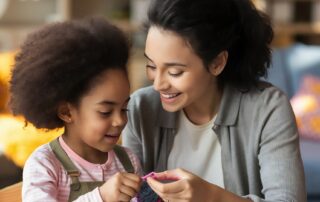 Parent supporting a child during a hands-on learning activity, illustrating ABA therapy techniques used in play-based sessions.