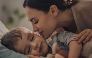 Mother comforting sleeping child with autism at home, representing caregiver support and respite care in Maryland – The Learning Tree ABA