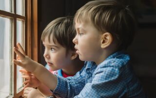 Children looking out a window together showing curiosity and connection while learning how to understand autism, representing sibling support and guidance by The Learning Tree ABA