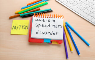 Notebook with autism spectrum disorder written on it alongside colorful markers, representing the autism diagnosis process for Maryland families