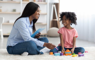 BCBA conducting a play-based initial assessment with a young child using colorful blocks on the floor, illustrating the naturalistic evaluation approach used at The Learning Tree ABA in Maryland