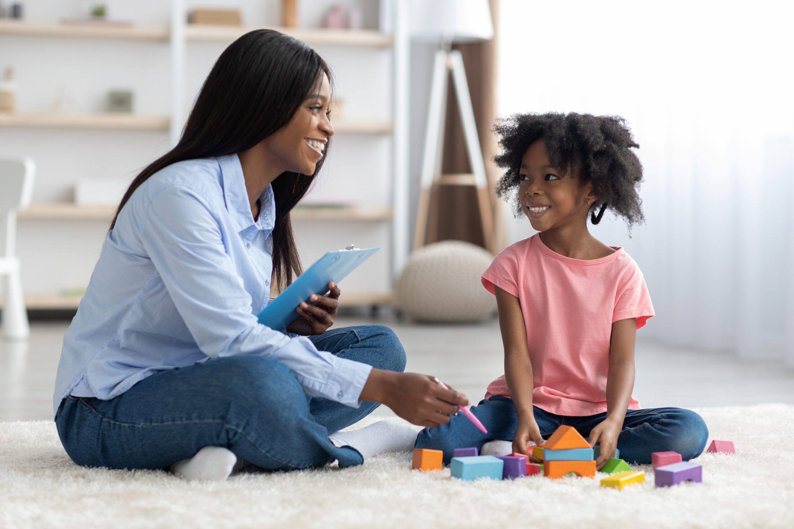 BCBA conducting a play-based initial assessment with a young child using colorful blocks on the floor, illustrating the naturalistic evaluation approach used at The Learning Tree ABA in Maryland