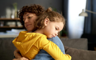 Mother calmly embracing and co-regulating with her child with autism after a challenging behavior episode at home in Maryland