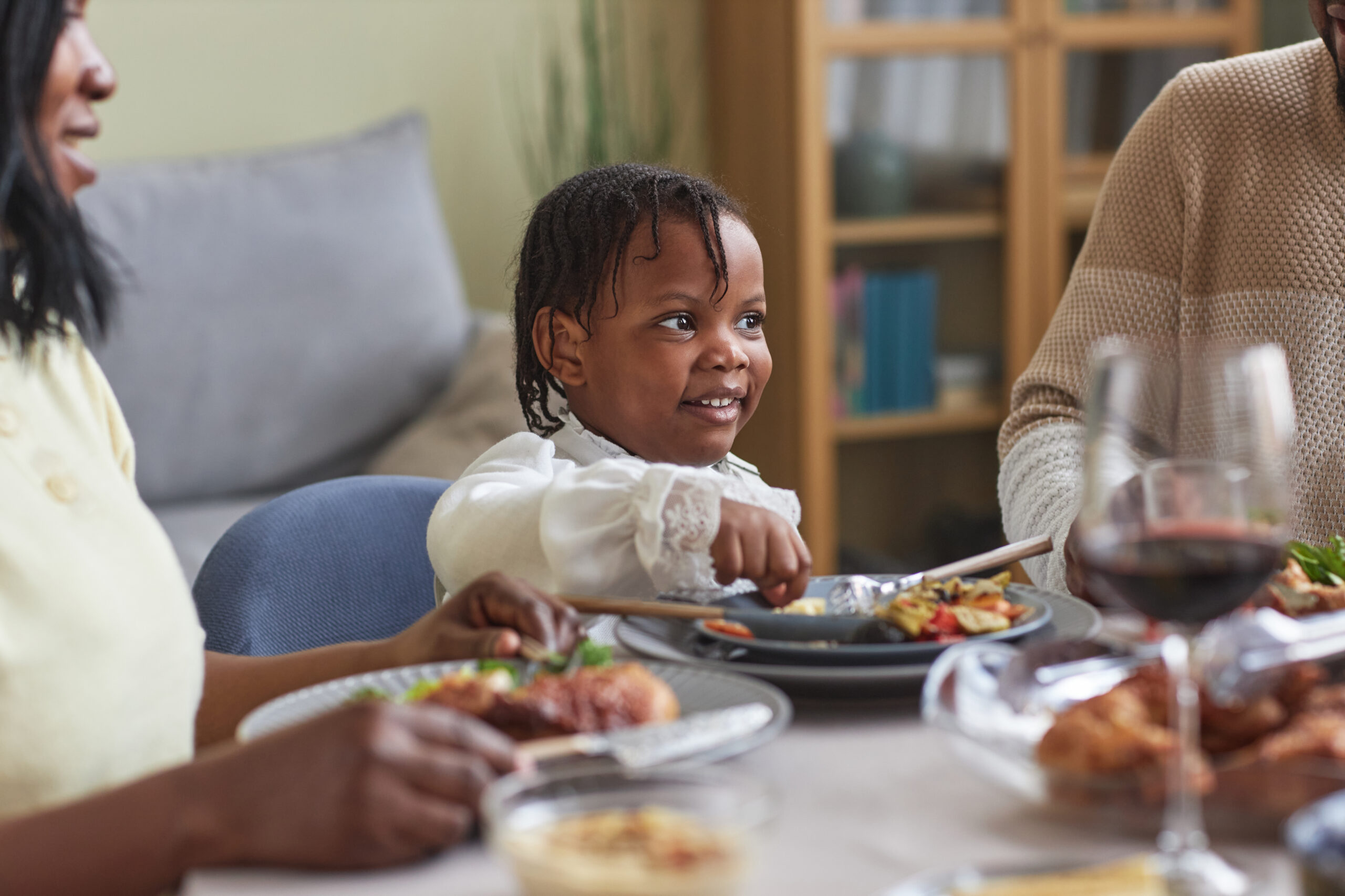 Young child with autism happily participating in a family meal at the dinner table, representing the goal of ABA feeding therapy for food selectivity in Maryland