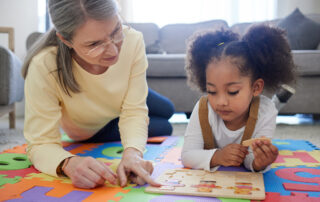 Behavior technician working one-on-one with a young child on a puzzle during an ABA therapy session at home in Maryland, illustrating the play-based approach used at The Learning Tree ABA